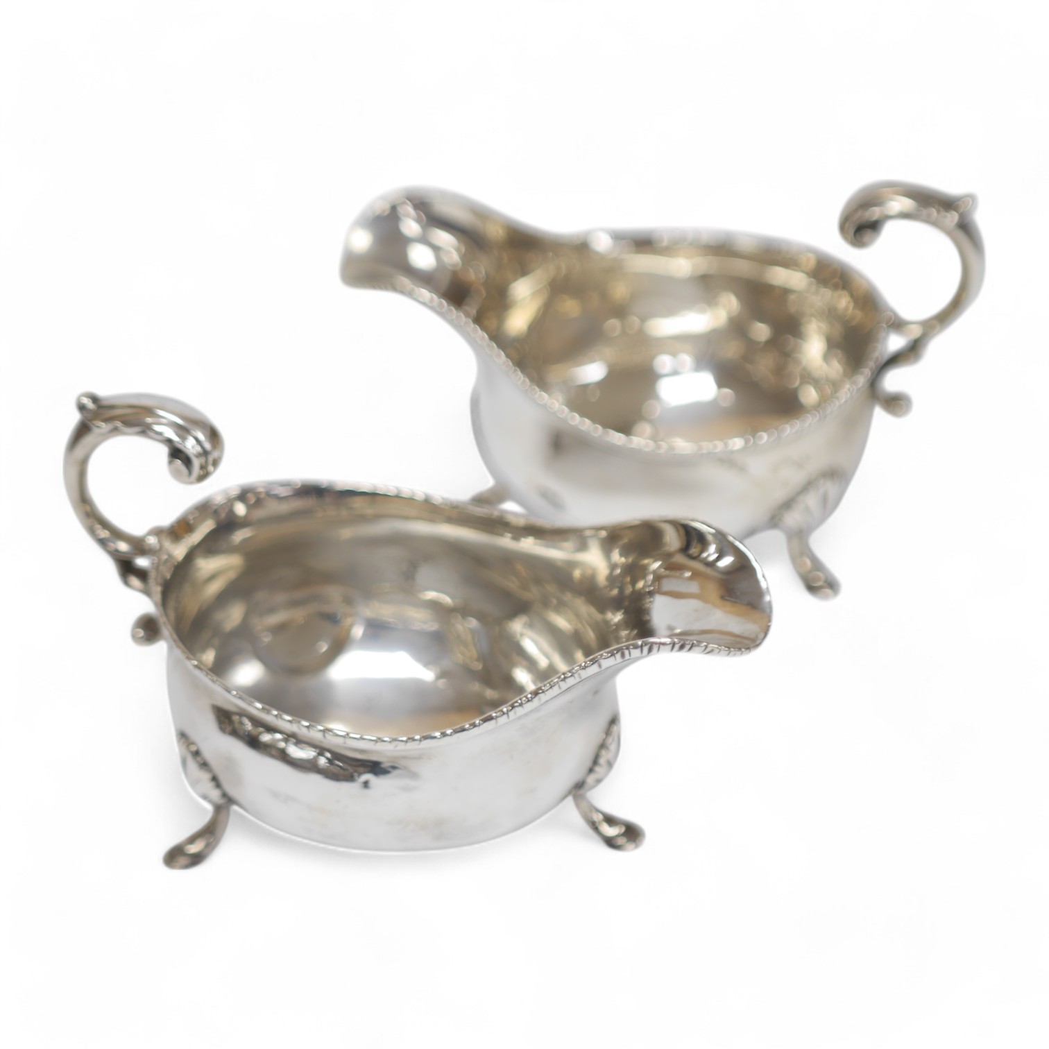 A pair of early George III silver sauce boats, with flying scroll handles, marks rubbed, London, 1765, length 16.3cm, 13.6oz, both patched and repaired. Condition - poor